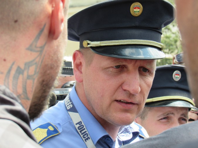 A police captain looks and sounds decidedly uncomfortable as he consults with skinheads hired to guard a public institution. Photo: C. Adam