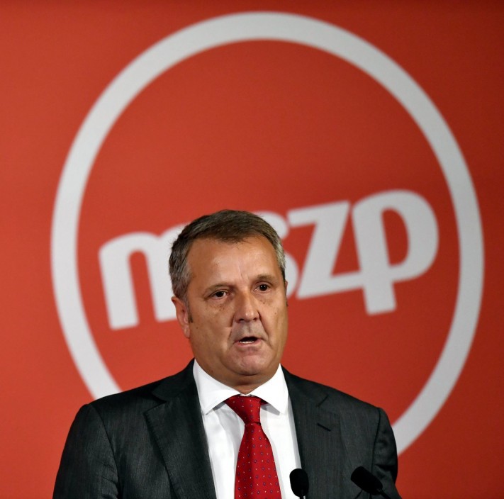 Gyula Molnár standing in front of the MSZP logo.